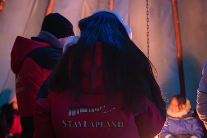 Guests warming up during StayLapland’s Kuoksa Reindeer Adventure long sleigh ride in Rovaniemi.