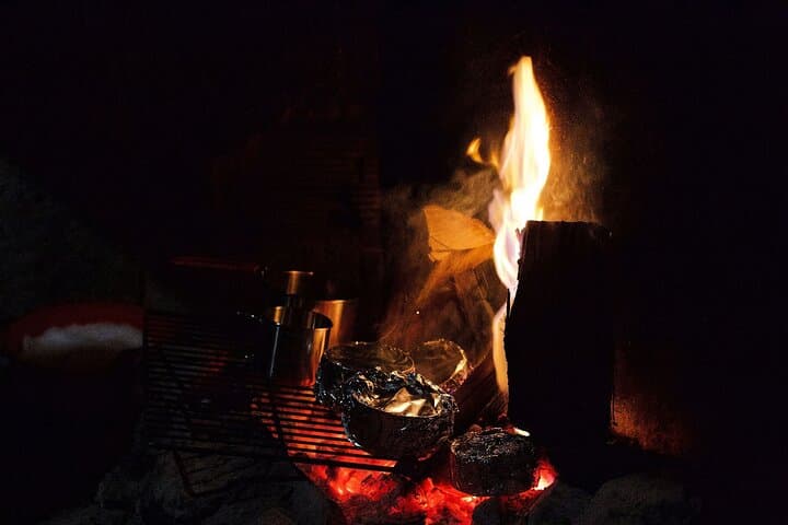 Warm drinks by the fire during a night skiing tour in Ylläs