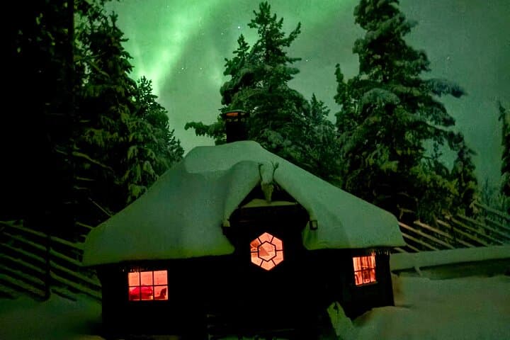 A cozy wilderness kota glowing under the Northern Lights near Levi.