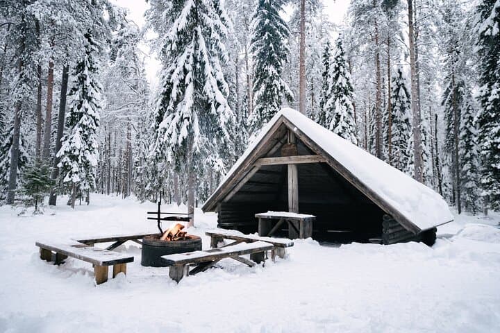 Cozy forest shelter with a campfire in snowy Lapland