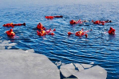 Ice floating in safety suit in frozen lake, an arctic experience to remember